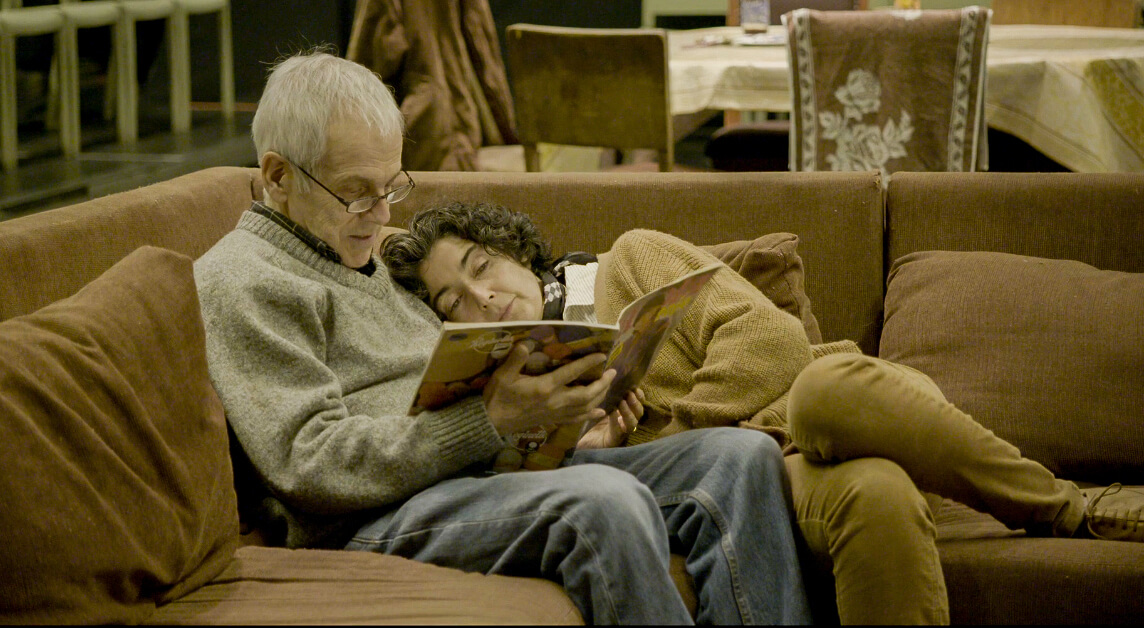Still from The Eternal Memory. Augusto and Paulina reading from a magazine on a sofa.