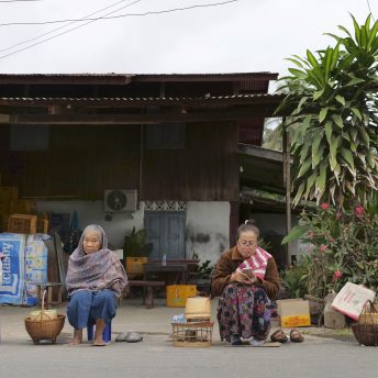 People sit waiting on the street early in the morning in Luang Prabang, Laos to give alms to the monks.