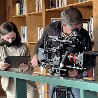 Production still from The Eternal Memory. Maite Alberdi working with an Ipad in her hands and a cameraperson working with a camera.