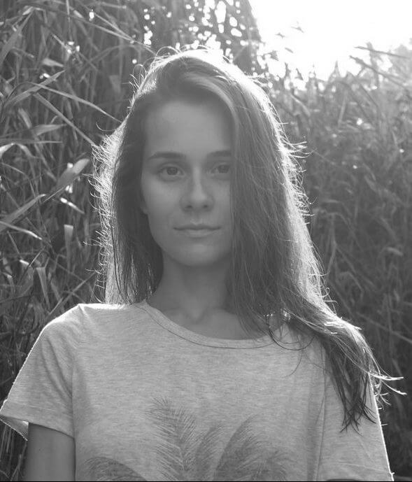 Olha Zhurba looking directly at the camera. She is standing in a field and is surrounded by tall crops. Black and white portrait. Credit - Viktor Zalevsky