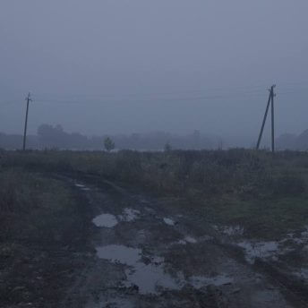 Production still of Intercepted. A muddy path in Kharkiv is shown. There are tracks left behind by tanks in the foreground. Various puddles of water are additionally on the ground. In the background, there are electric polls and dark, gray clouds.