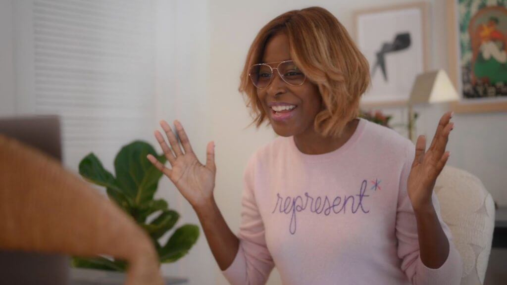 Still from Breaking the News Film. Editor-at-large Errin Haines is smiling directly at the camera in a pink sweatshirt that reads "Represent."