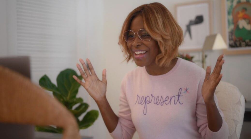 Still from Breaking the News Film. Editor-at-large Errin Haines is smiling directly at the camera in a pink sweatshirt that reads "Represent."