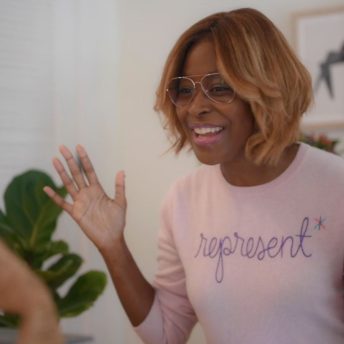 Still from The Untitled 19th* News Film. Editor-at-large Errin Haines is smiling directly at the camera in a pink sweatshirt that reads "Represent."