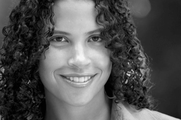 Lacey Schwartz Delgado looks directly at camera and smiles. Black and white portrait.