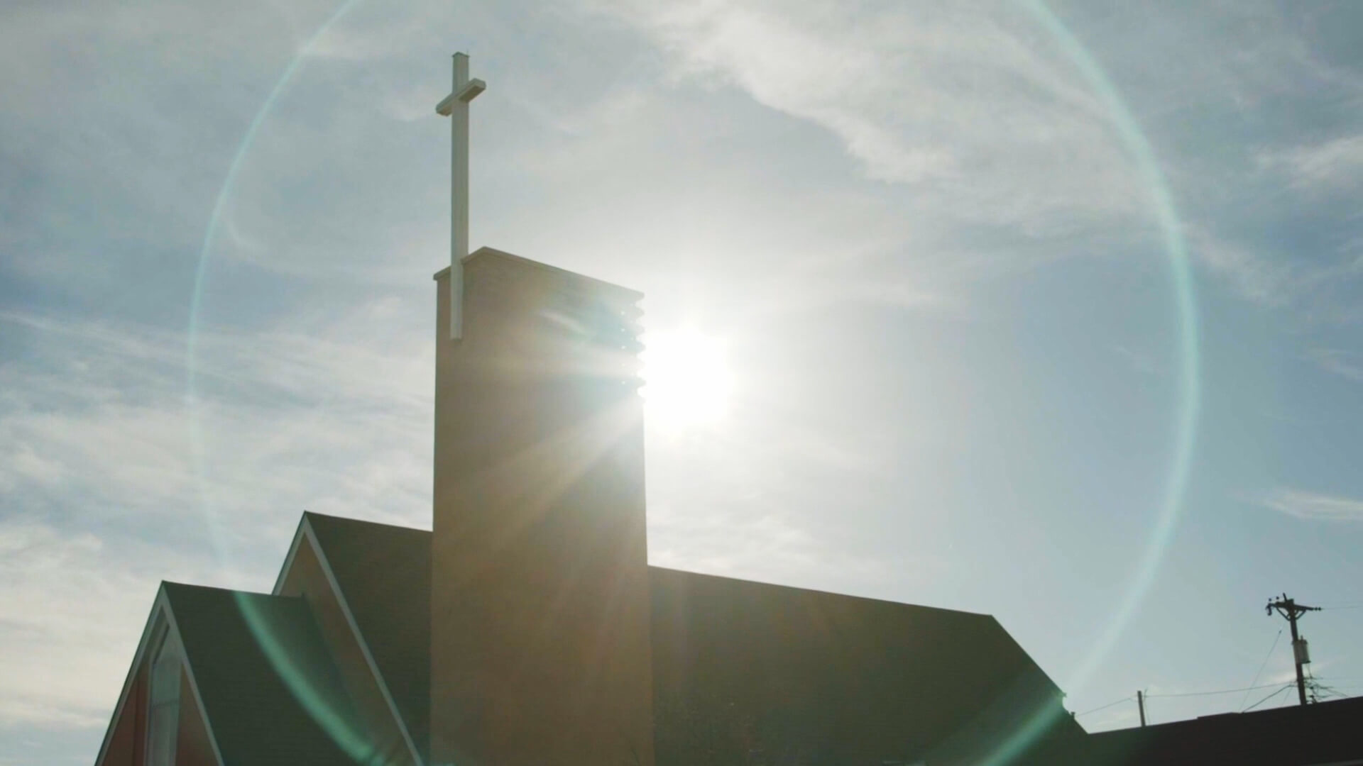 Sun halo around church spire with cross.