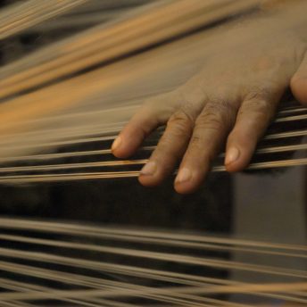 A workers hand on jute threads as they pass through the spinning machine