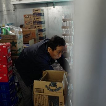 Liquor Store owner, Hae Sup Um stocks the beer fridge