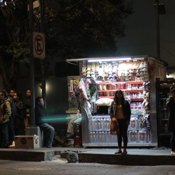Fernanda waits in front of a local store for a collective cab at night.