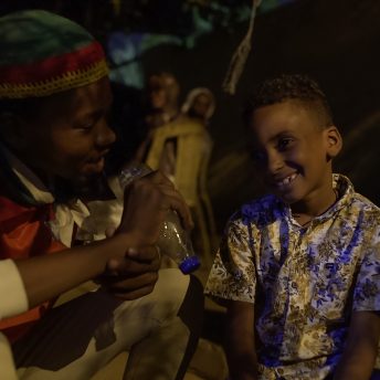 A Sudanese protestor interviews a young boy using a water bottle as a microphone.