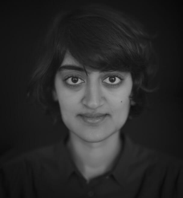 A black and white portrait of Roopa Gogineni looking at the camera.