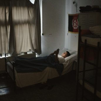 We see a young man (Sajid Khan) lying on his bed, with the windows drawn, looking on his phone. His face is illuminated by the light of his screen, we can see it is light outside, behind the closed curtains.