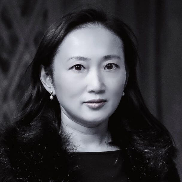 This is a headshot of Violet Du Feng in black and white image, in which she wears a a fluffy jacket and pearl earrings with hair down over her shoulder.