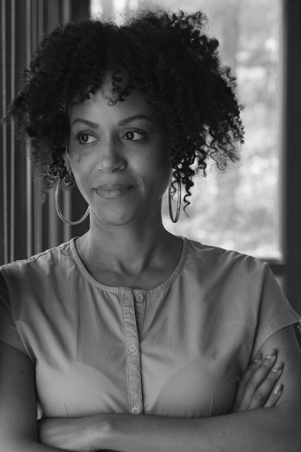 Portrait of Nailah Jefferson. Nailah looks away from camera with arms crossed. Black and white.