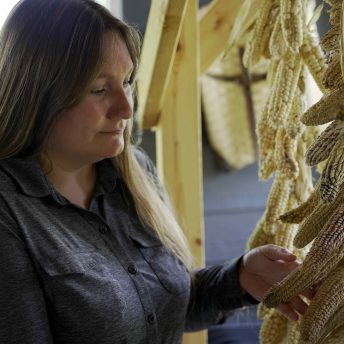 Oneida farmer, Rebecca Webster, with her heirloom corn that is braided and hung out to dry inside her home.