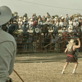 A rodeo clown in women's drag uses a lasso
