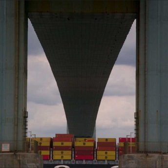 Still from Union. Loading dock of ship with shipping containers under a bridge.