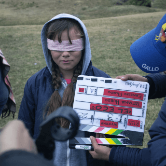 A producer holds a clapperboard over a blindfolded little girl's face.