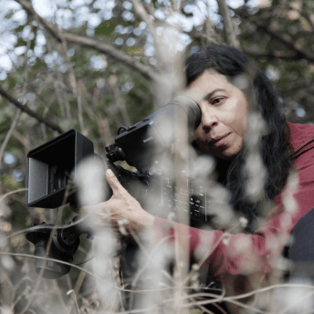 Tatiana Huezo adjusts her camera while filming in the woods.